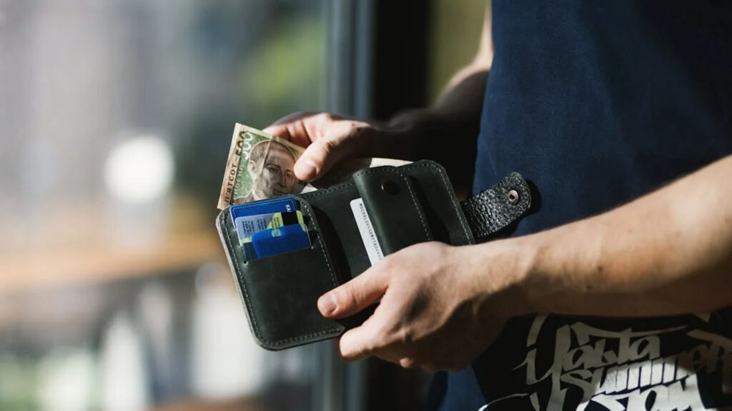 Close-up of a man holding a wallet with cash