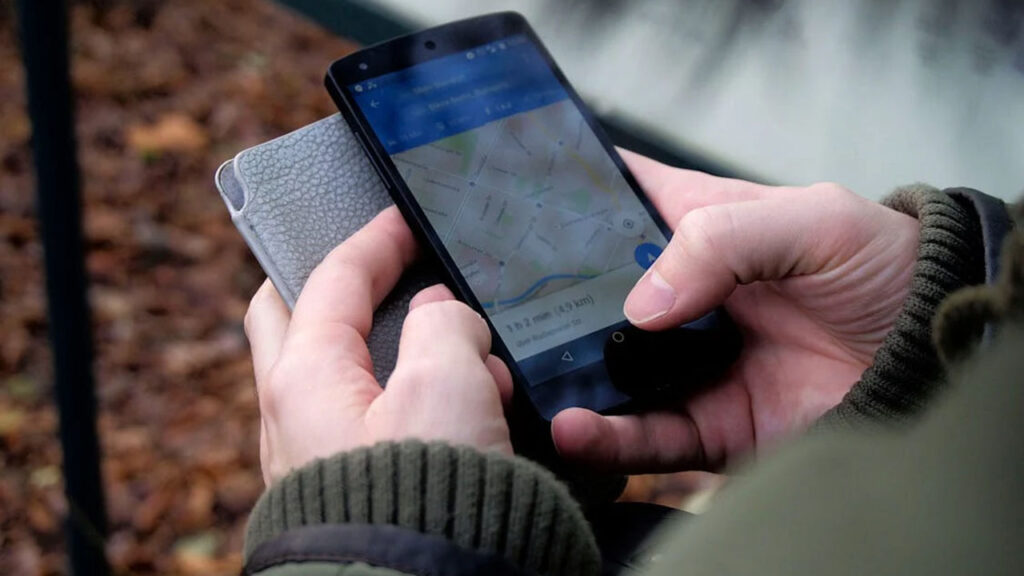 Close-up of hands using a map app on a smartphone outdoors