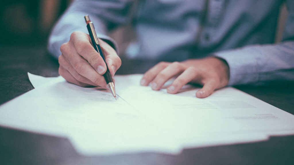 man writing on paper about laws