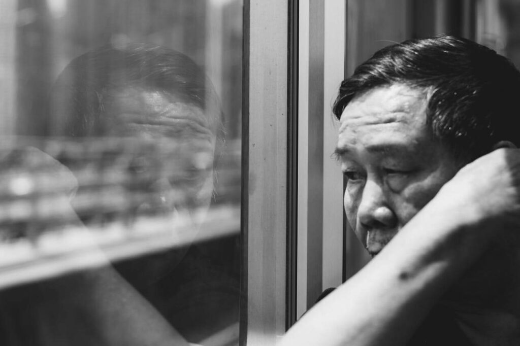Sad old man looking at the window